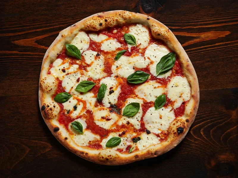 Pizza margherita aux feuilles de basilic sur une table en bois rustique