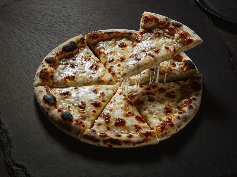 Pizza quatre fromages dont une part laisse filer le fromage fondu